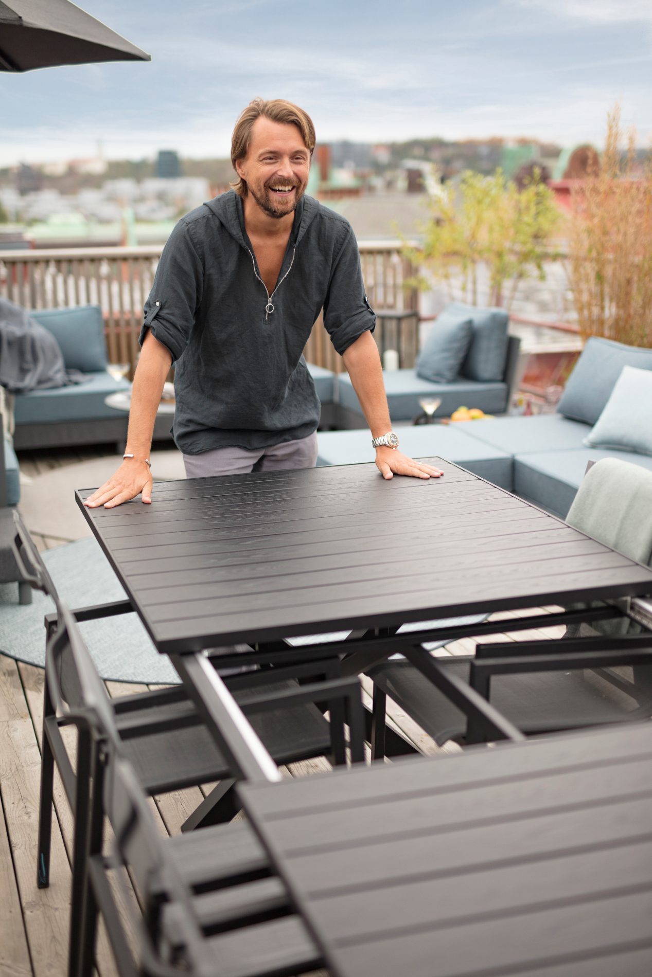 Mann zieht lachend Gartentisch aus